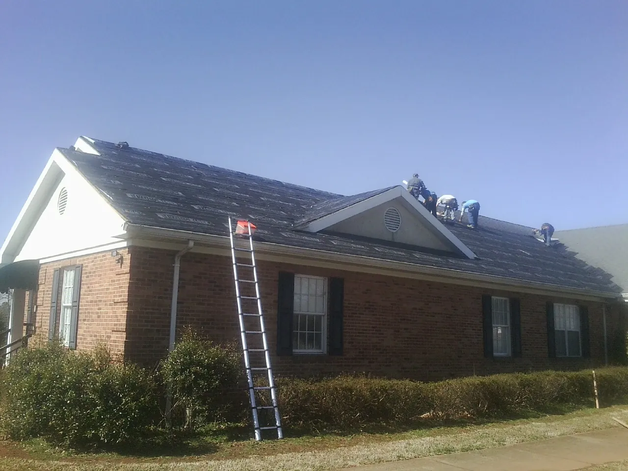 Crew tearing shingles off a brick ranch roof with a ladder set — Metal Roof Repair work by our crew in Menifee