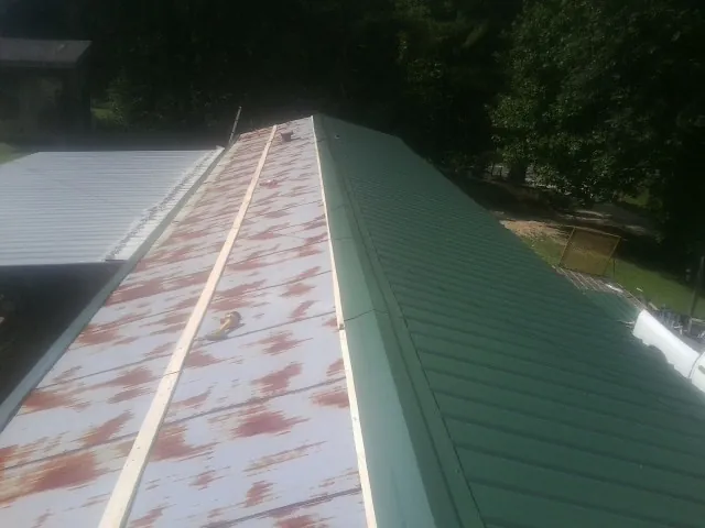 Old rusted panels beside newly installed green metal roofing — Wind Damage Roof Repair by Roofing Brothers in Menifee