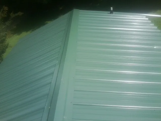 New green metal panels meeting at the ridge of a roof — Flat Roof Repair work by our crew in Menifee
