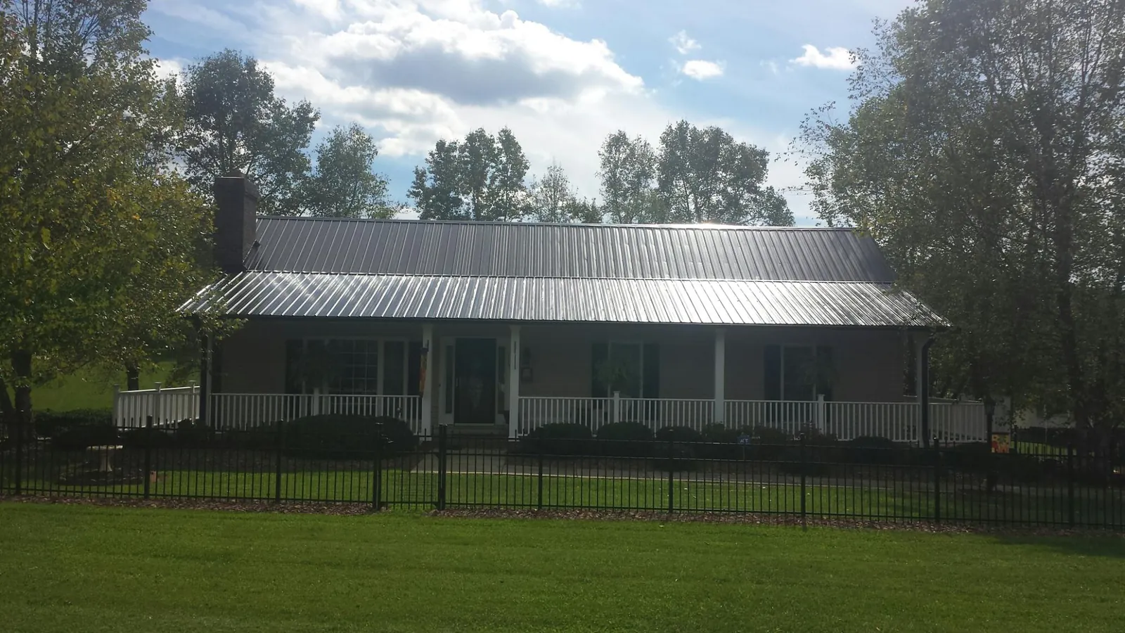Gray metal roof on a brick ranch with a full width front porch — Gutter Guard Installation work by our crew in Menifee