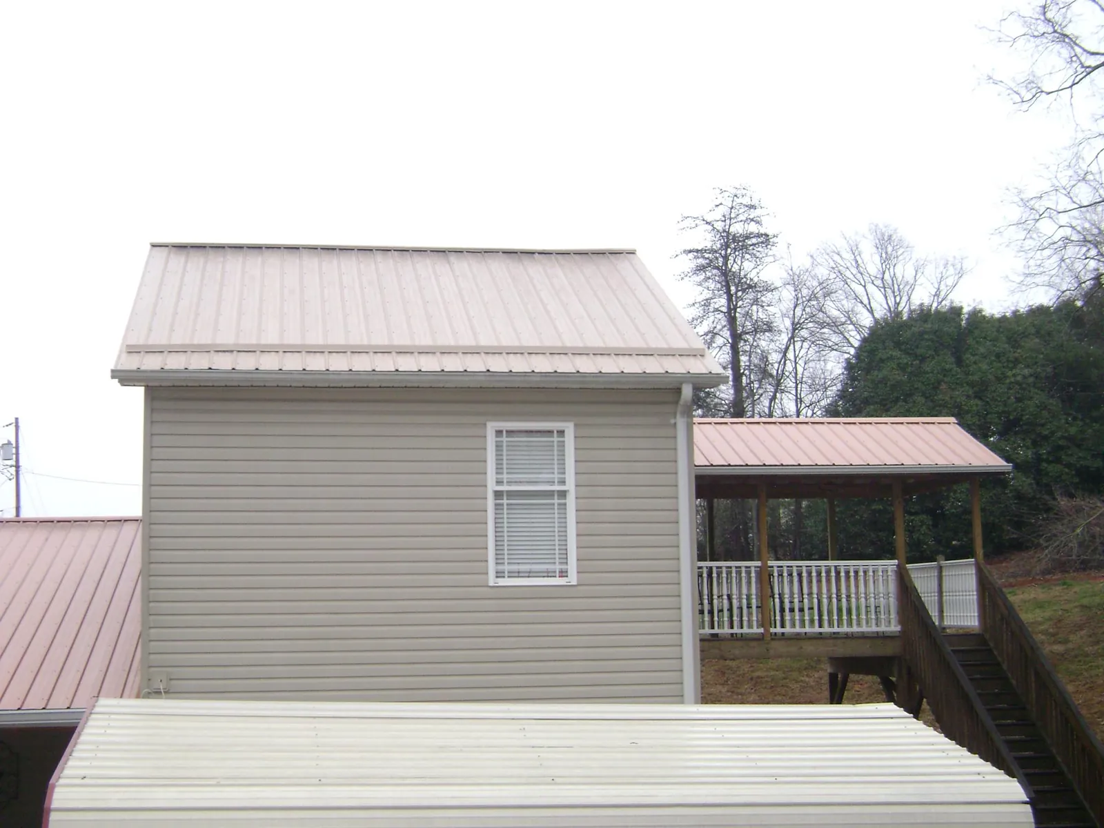 Tan metal roofs on a two story addition and attached porch, from a Roof Replacement job in Menifee